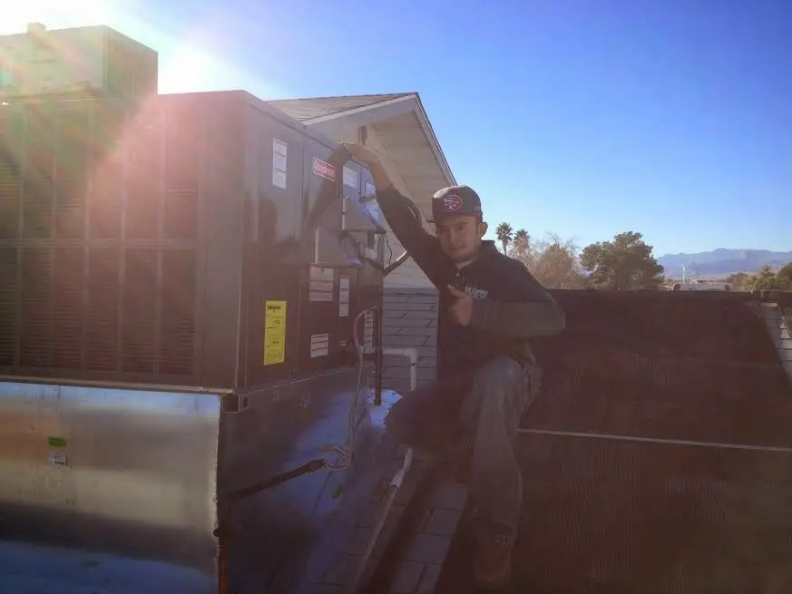HVAC technician performing Air Duct Cleaning on a rooftop unit in Abington